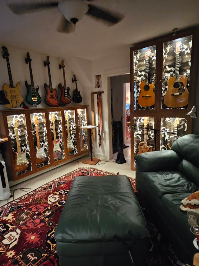 Guitars on the wall beside the green leather sofa.