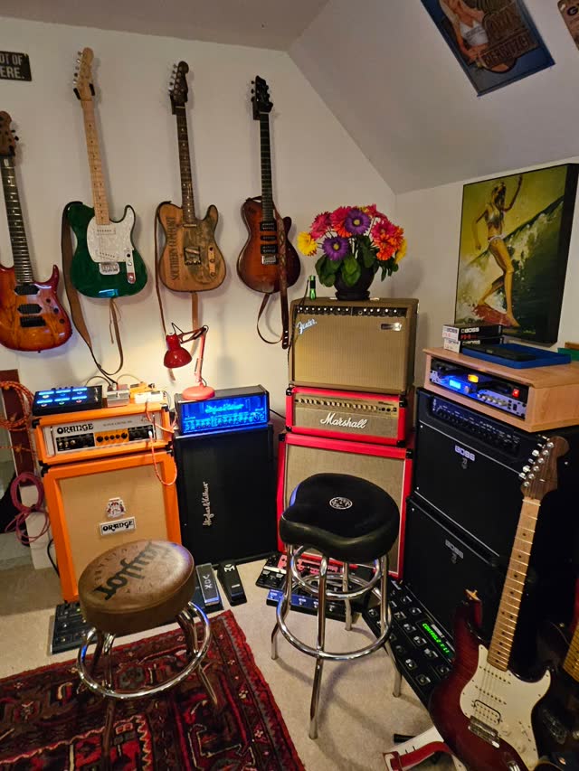 The amp corner: Orange and Marshall amps, guitars on the wall.