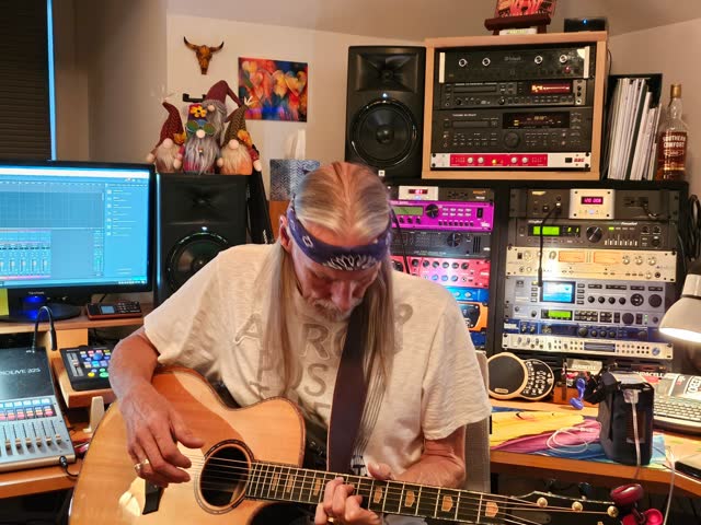 Steve playing an acoustic guitar at the console.